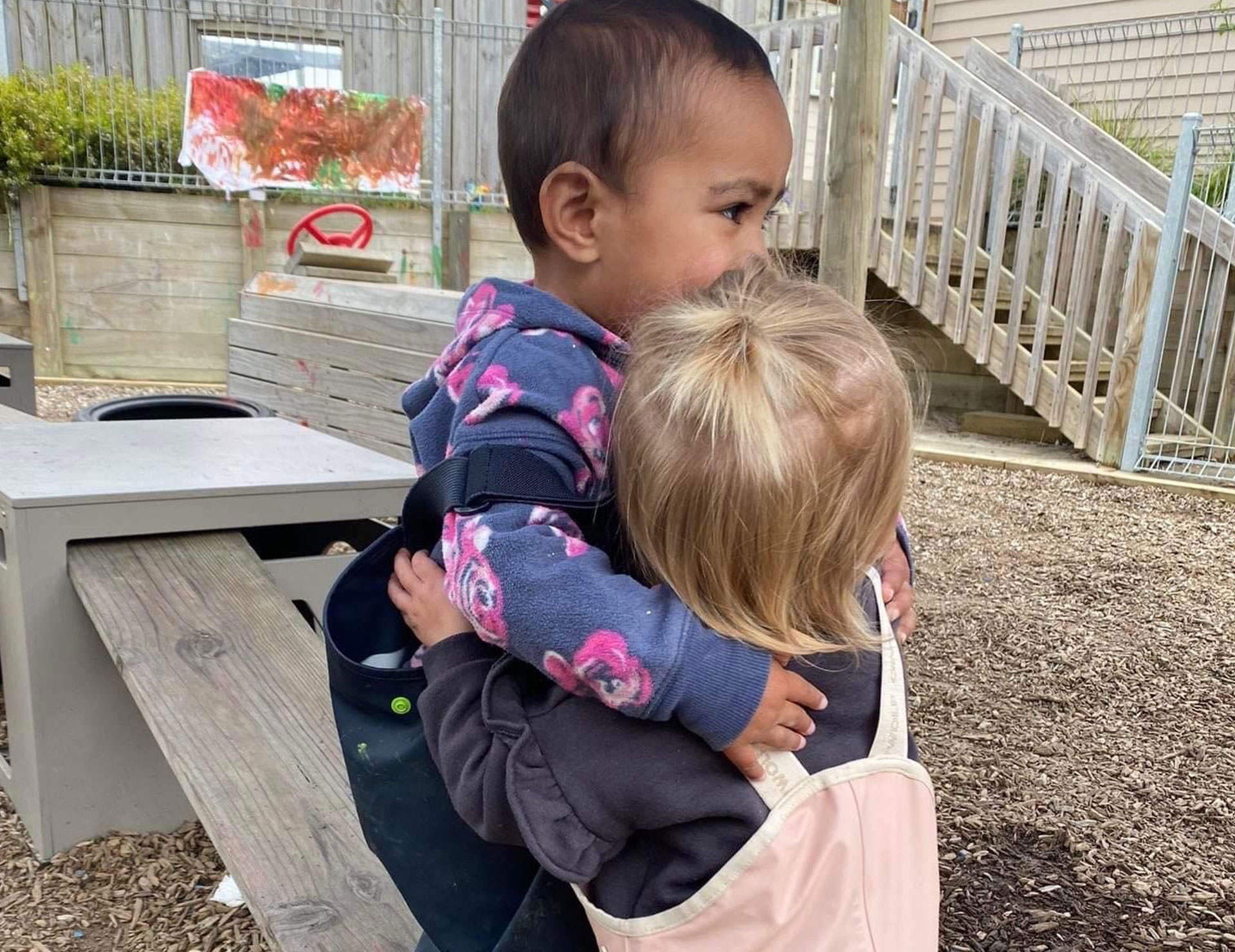 Photo of two toddlers hugging each other outside